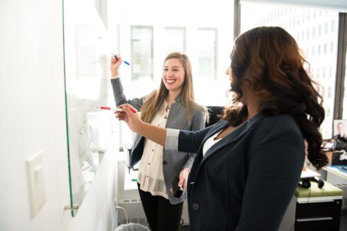 two event planners creating a conference agenda on a whiteboard